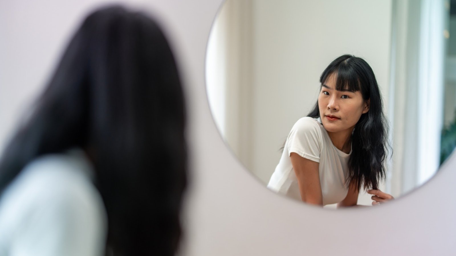 Woman looking at her reflection in the mirror, representing self-reflection and emotional healing after past experiences